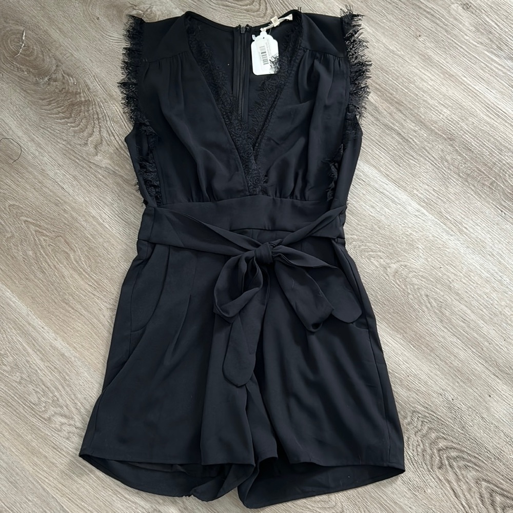 Black pleated front romper with lace trim sleeves and neck line